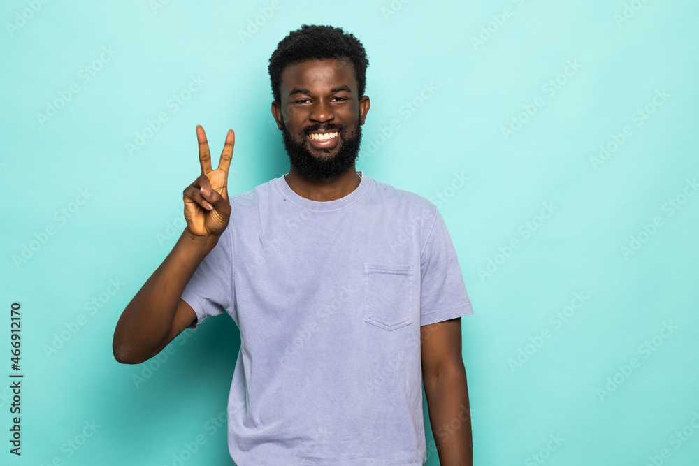 Positive cheerful handsome man raise hand show v-sign over green background Positive cheerful handsome man raise hand show v-sign over green background
