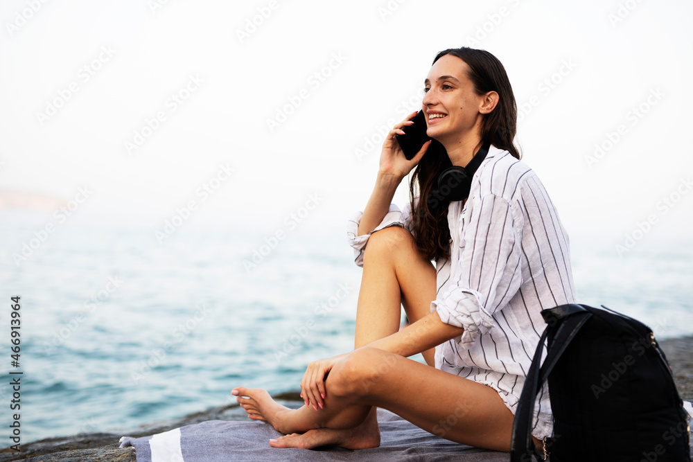 Happy young woman relaxing on the sandy beach. Beautiful woman talking to the phone.