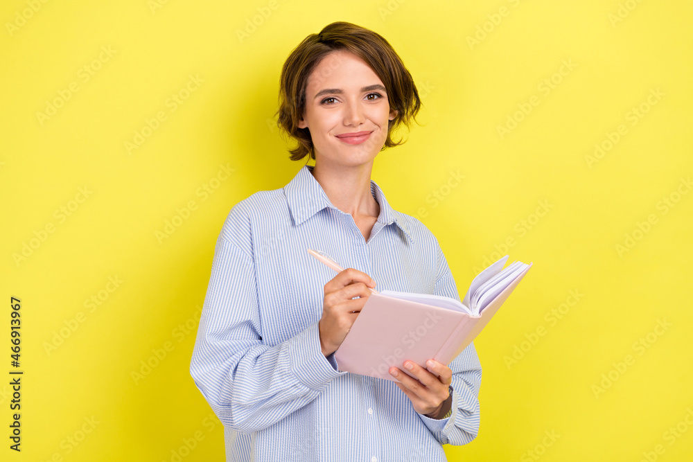 Photo of young attractive woman happy positive smile write notes idea isolated over yellow color background Photo of young attractive woman happy positive smile write notes idea isolated over yellow color background