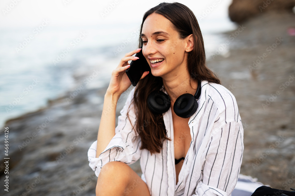 Happy young woman relaxing on the sandy beach. Beautiful woman talking to the phone. Happy young woman relaxing on the sandy beach. Beautiful woman talking to the phone.