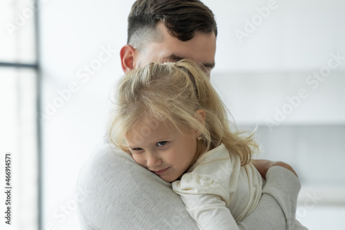 Portrait of a cute little girl in her father's arms. A father and his daughter, a baby girl, play cuddling.