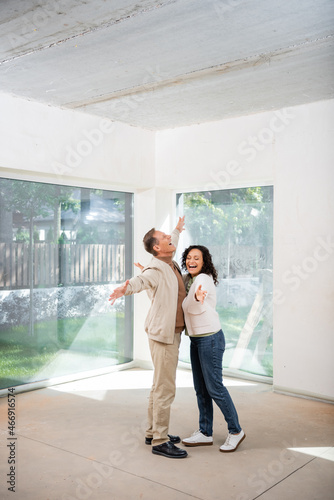 excited man and african american woman rejoicing in new house