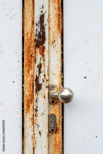 A white door with a rusted metal frame and orange and brown structures