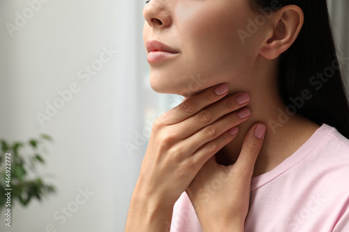 Young woman doing thyroid self examination indoors, closeup. Space for text