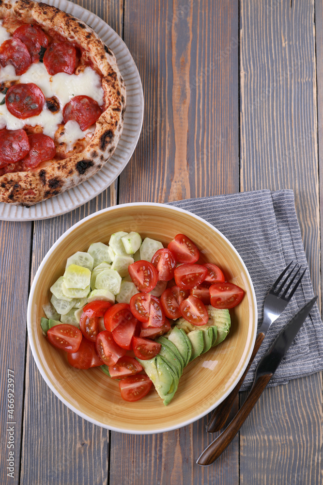 Neapolitan pizza with pepperoni and vegetable salad Neapolitan pizza with pepperoni and vegetable salad