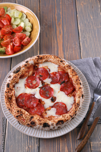 Neapolitan pizza with pepperoni and vegetable salad