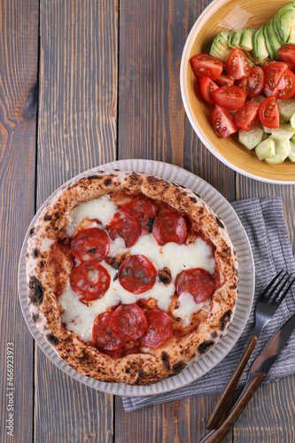Neapolitan pizza with pepperoni and vegetable salad