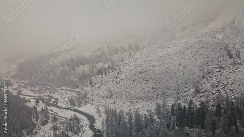 Storm, snowfall in the huge glacier of Mount Belukha, the valley of the Aktru River, the Altai Mountains. Cloudy weather, stone in the snow, storm, wildlife, winter forest, frozen mountain river in