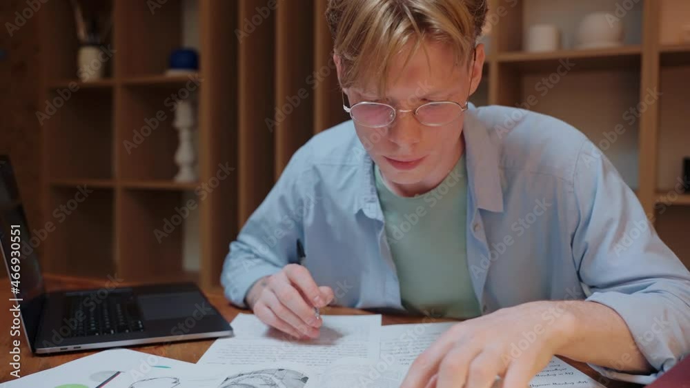 Guy searching through the dictionary book and writing in his notes.Young man studying in warm wood room. Doing homework in the evening. High quality 4k footage Guy searching through the dictionary book and writing in his notes.Young man studying in warm wood room. Doing homework in the evening. High quality 4k footage