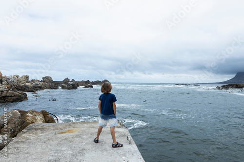 8 year old boy looking at the ocean,jetty, Kleinmond, South Africa photo