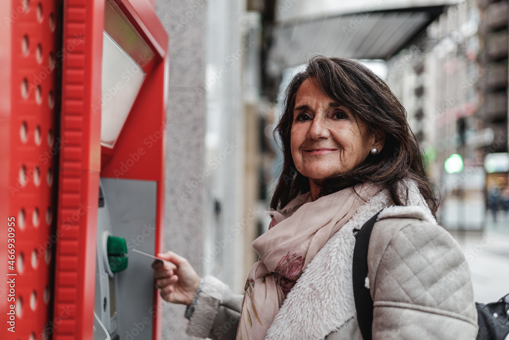 mature woman taking money from an ATM on the street