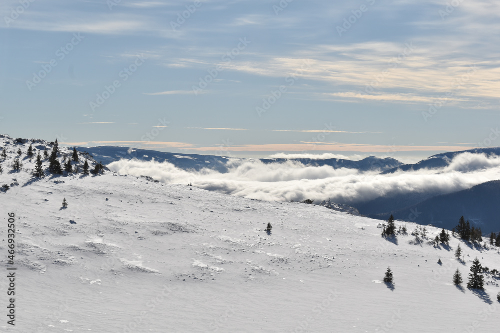 Verschneite Berglandschaft mit Wolkenmeer und blauem Himmel, Skitour im Wintertourismus