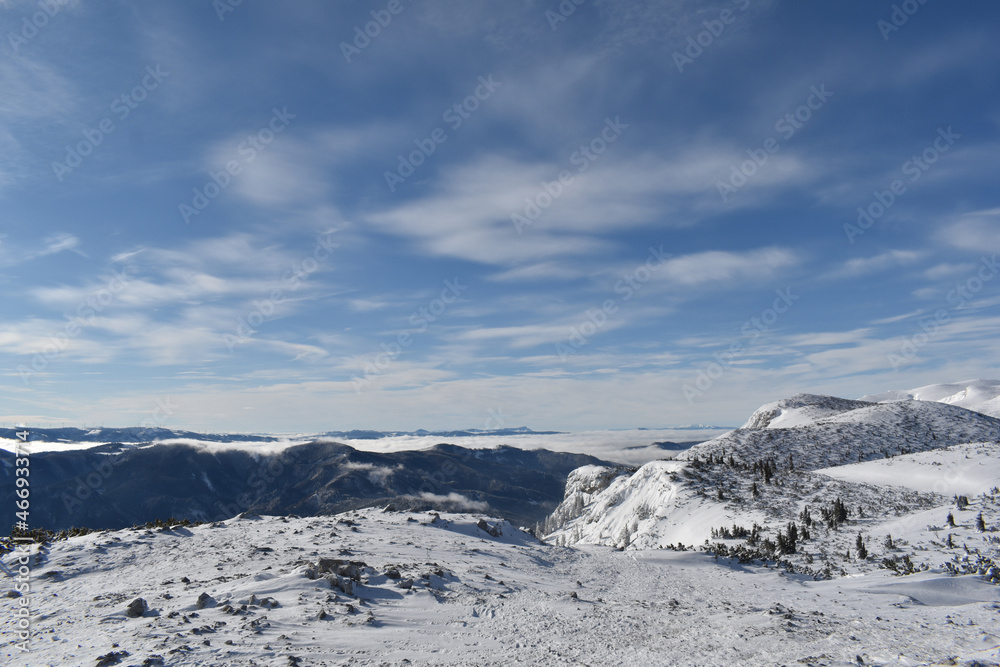 Verschneite Berglandschaft mit Wolkenmeer und blauem Himmel, Skitour im Wintertourismus	
