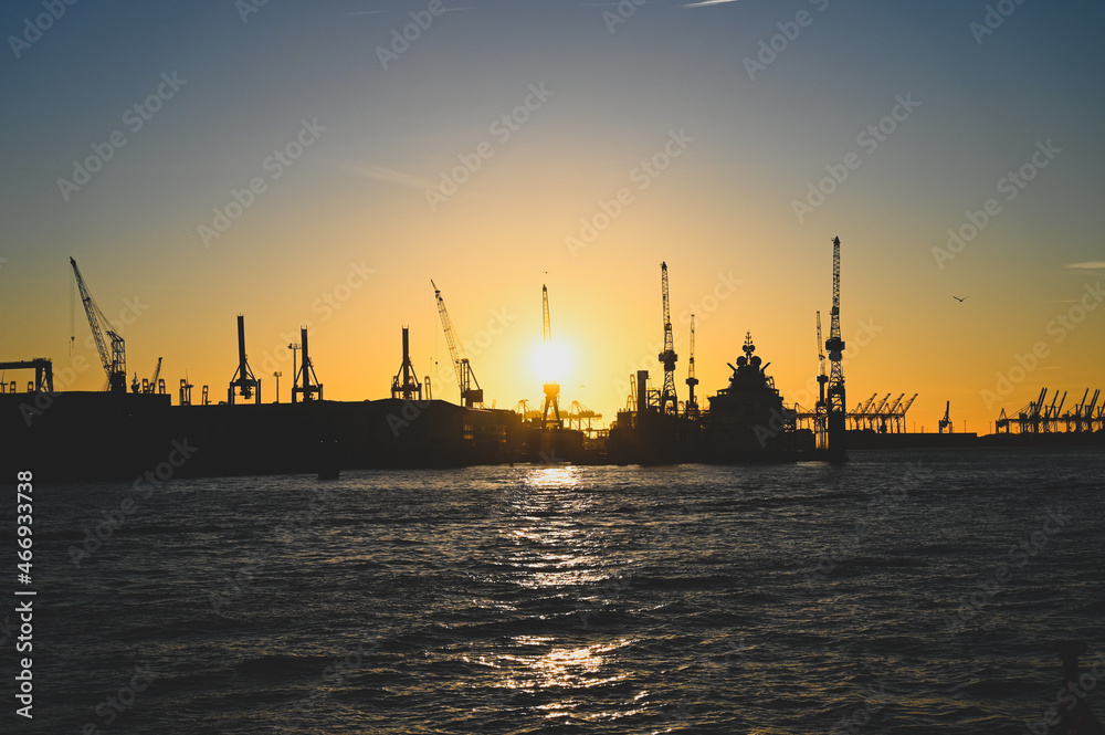 Harbour in Hamburg, Germany. Cranes in shipyard at sunset. Seaport on Elbe river. Jackup rig, Oil platform and Container crane in Dockyard. Ship port. Industry and transport. Shipbuilding.  