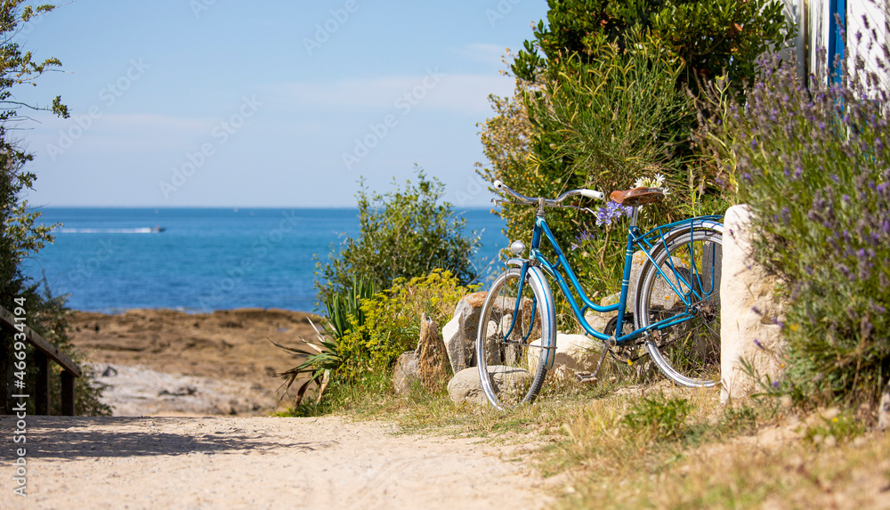 Fototapeta premium Vieux vélo bleu en bord de mer sur une plage de Bretagne en France.