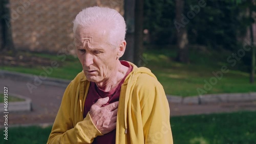 Senior man feeling shortness of breath, heartache after jogging in park photo