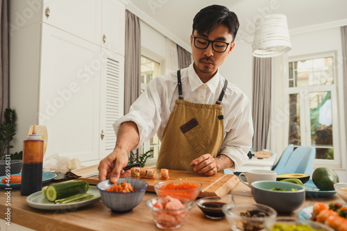 Asian sushi master making sushi rolls on a kitchen background. ingredients for sushi on a table