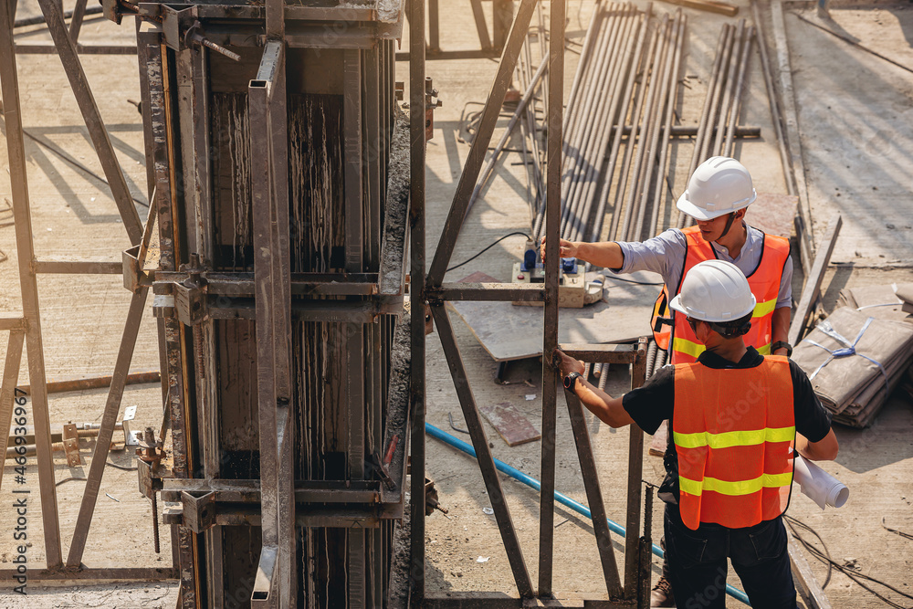 Structural engineer and foreman worker with blueprints discuss, plan inspecting for the outdoors building construction site.