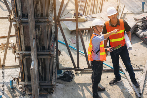 Structural engineer and foreman worker with blueprints discuss, plan inspecting for the outdoors building construction site.