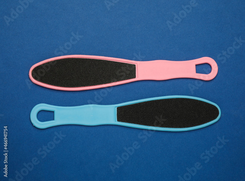 Colorful foot files on blue background, flat lay. Pedicure tools
