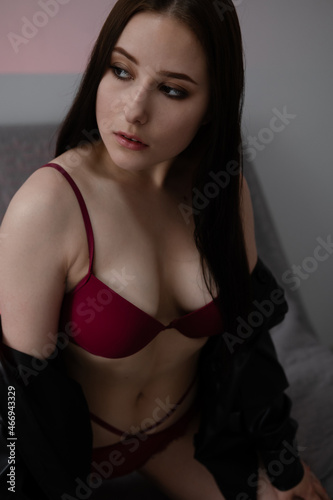 portrait of brunette woman in red underwear in dark grey room © OliaVesna