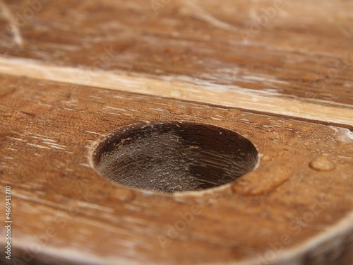 Loch im Holzbrett mit Wassertropfen etwas zerkratzt 