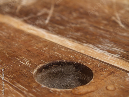 Loch im Holzbrett mit Wassertropfen etwas zerkratzt 