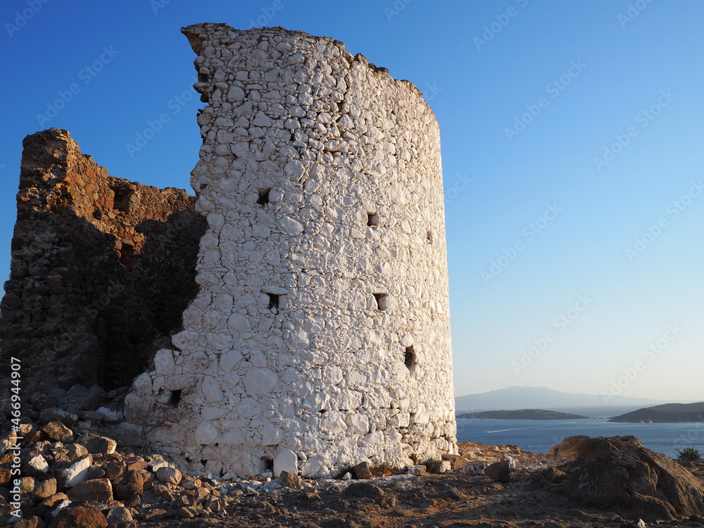 Ancient dilapidated mills on a mountain cape, against the background of the blue sea and the summer sky