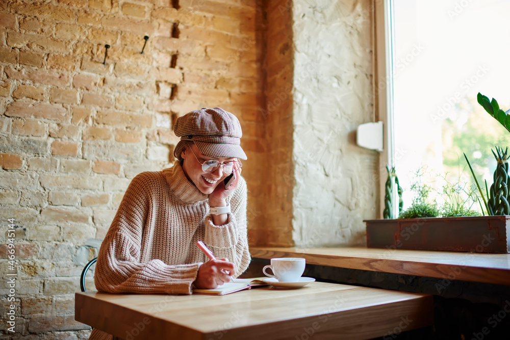 Fototapeta premium Happy woman talking on phone and writing notes