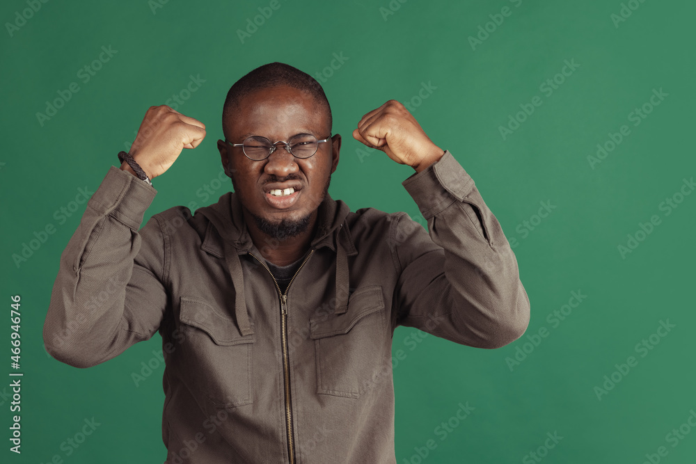 Winning success happy man celebrating being a winner. Dynamic image of male model isolated on dark green studio background Winning success happy man celebrating being a winner. Dynamic image of male model isolated on dark green studio background