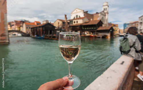 Dinner time with white wine in hand. Venice with canals and embankments with bar and restaurants of famous italian city.