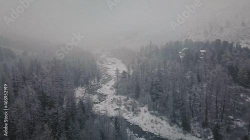 Storm, snowfall in the huge glacier of Mount Belukha, the valley of the Aktru River, the Altai Mountains. Cloudy weather, stone in the snow, storm, wildlife, winter forest, frozen mountain river in