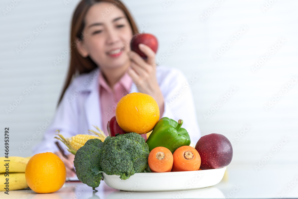 Blurred soft images of Asian woman doctor, nutritionist holding fresh fruit, vegetables with high vitamin C, Useful to the body, On white background to health care and clean food concept. Blurred soft images of Asian woman doctor, nutritionist holding fresh fruit, vegetables with high vitamin C, Useful to the body, On white background to health care and clean food concept.