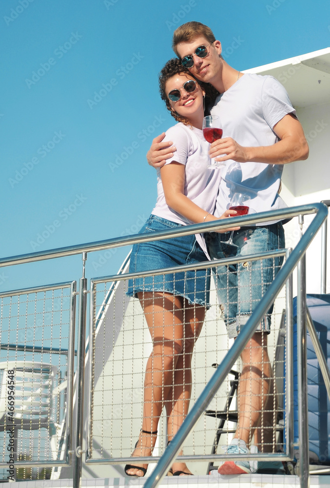 Happy family vacation. Smiling couple with wine glasses and suitcase on the ship. Man and woman goes on a summer vacation. Happy family vacation. Smiling couple with wine glasses and suitcase on the ship. Man and woman goes on a summer vacation.