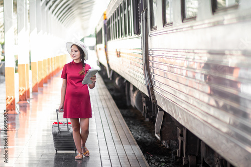 Asian woman pregnant of red dress travel with red suitcase in railway station travel,traveler with backpack in summer Holiday concept Thailand