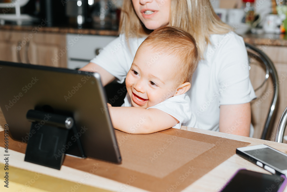 Mom and child using tablet together, watching educational children's video cartoons. Close-up laughing, joyful baby boy touching laptop display. Motherhood, parenting, child care concept Mom and child using tablet together, watching educational children's video cartoons. Close-up laughing, joyful baby boy touching laptop display. Motherhood, parenting, child care concept