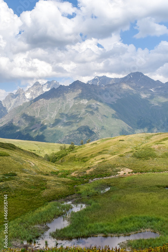 Summer mountain landscape in Svaneti region, Georgia, Asia. Snowcapped mountains in the background. Blue sky with clouds above. Georgian travel destination