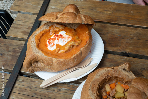 Hungarian goulash in bread bowl on wooden table. Street food in Budapest, Hungary.