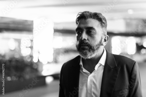 Canvas Print Black and white portrait of handsome Indian businessman in city at night thinkin