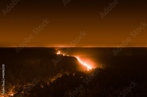 Smoky forest at night with light from the highway  which looks like a forest fire  aerial view.