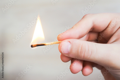 the child holds a lit match and it burns with a flame