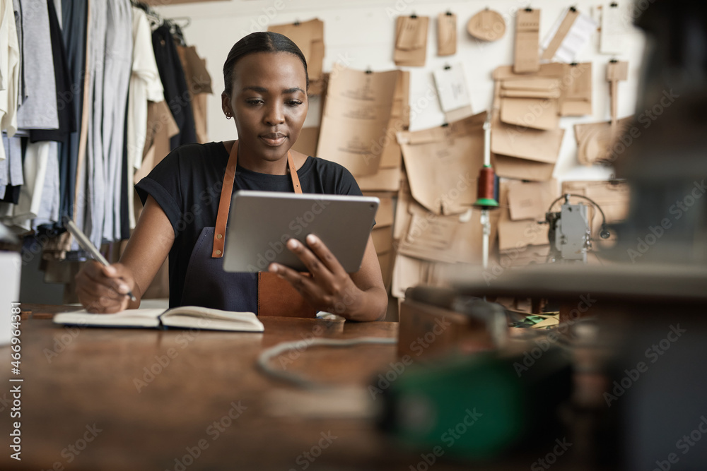 African female leather worker writing notes and using a tablet African female leather worker writing notes and using a tablet