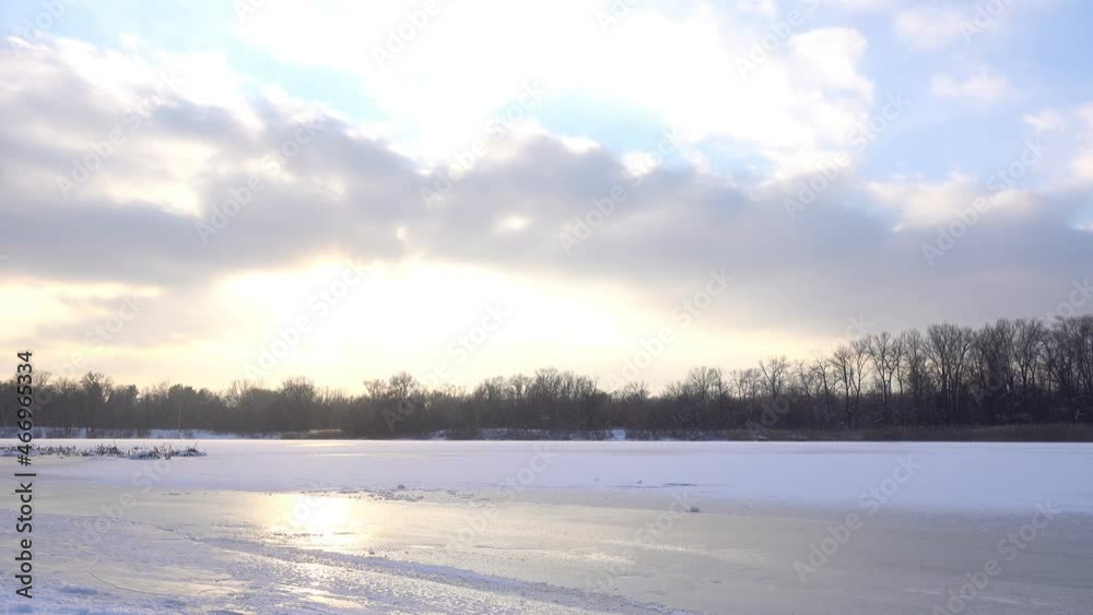 Frozen snow-covered river in the forest and clouds floating in the sky in time laps. Frozen snow-covered river in the forest and clouds floating in the sky in time laps.