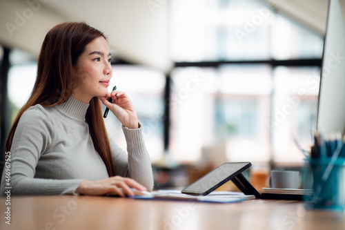 Shot of an Asian young businesswoman working on a laptop computer in her workstation.Portrait of Business people employee freelance online marketing e-commerce telemarketing concept.