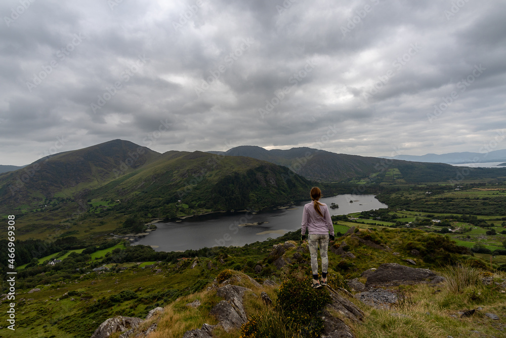 Young woman traveler looking at mountain and lake landscape in beara peninsula ireland