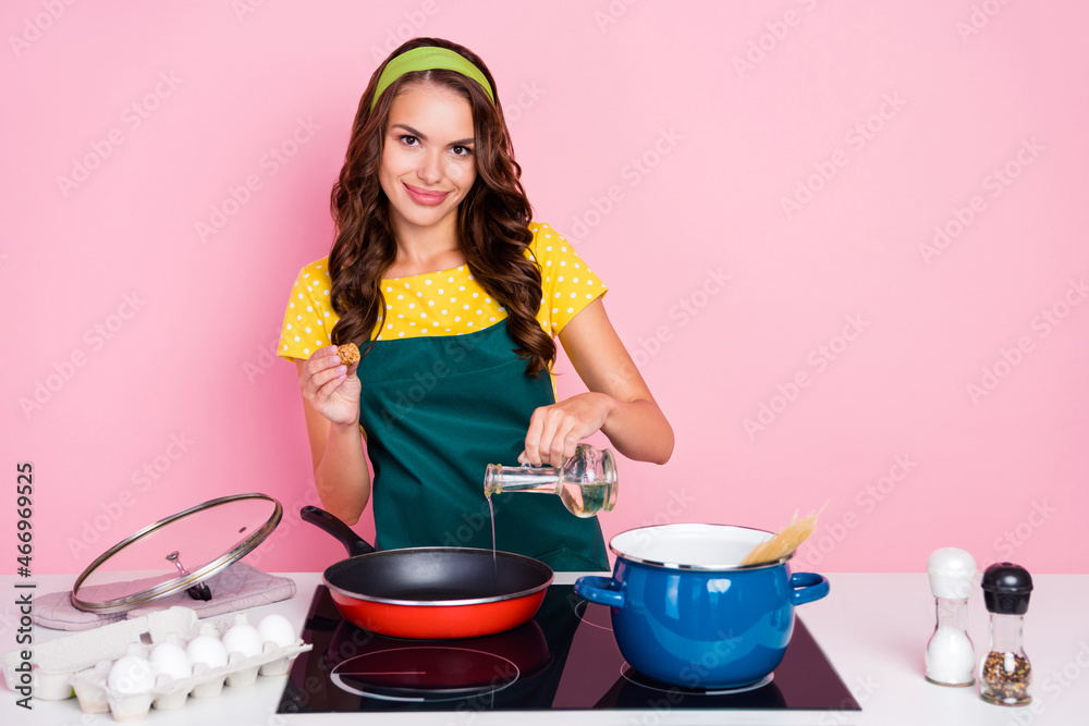 Photo of adorable pretty young woman wear green apron frying tasty breakfast smiling isolated pink color background Photo of adorable pretty young woman wear green apron frying tasty breakfast smiling isolated pink color background