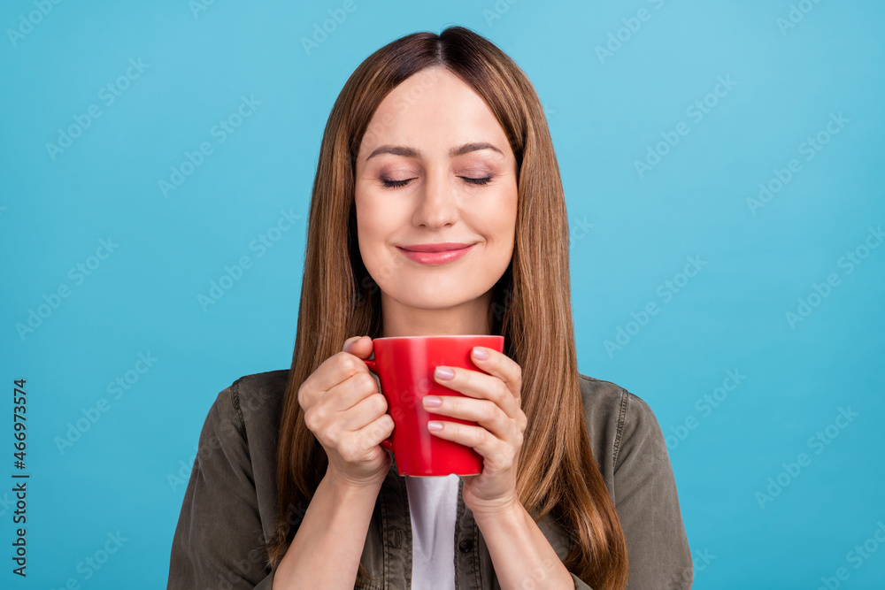 Photo of dreamy pretty mature woman hold hands cup of tea smell aroma enjoy isolated on blue color background Photo of dreamy pretty mature woman hold hands cup of tea smell aroma enjoy isolated on blue color background