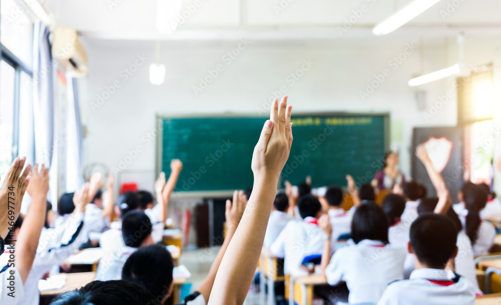 Rear view of raised hands in middle school classroom - obrazy, fototapety, plakaty 