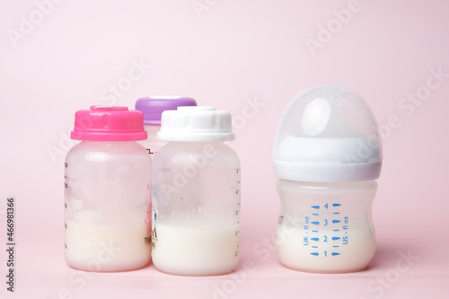 A picture of drink and three storage baby bottle on pink background. Breast milk is good source of calcium and protein for baby.