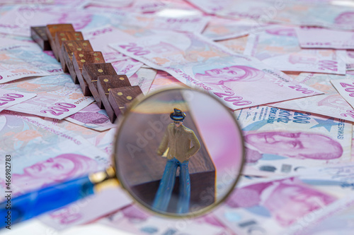 Turkish lira money, cash money with dominoes and magnifying glass. Miniature people standing on domino cubes with stacks of money. Saving money, finance, business, goal achievement concept. photo